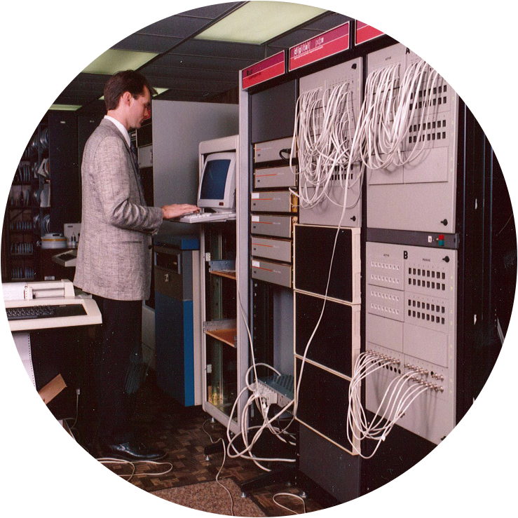 Man at Vintage CRT Terminal Beside Server Rack